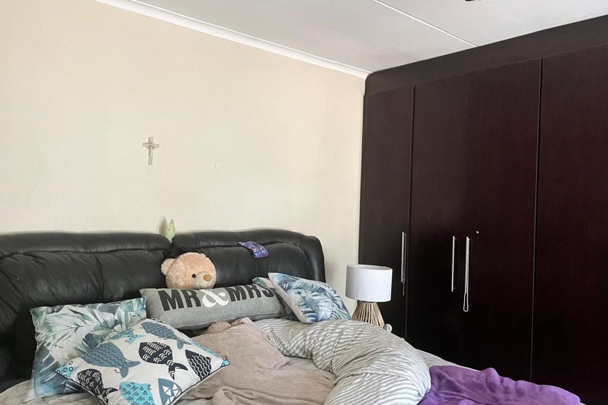 A bedroom featuring dark wood built-in wardrobes and a ceiling fan.