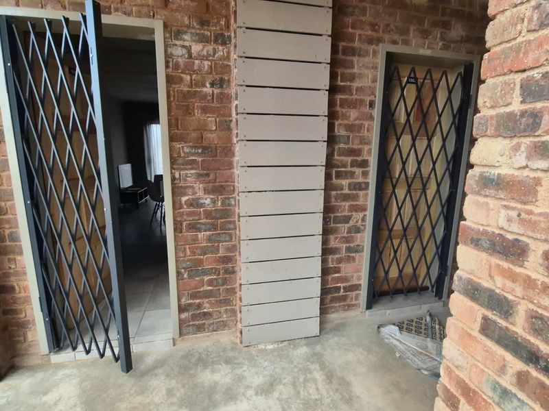 Entrance area featuring exposed brickwork, security gates, and unfinished wall cladding elements.