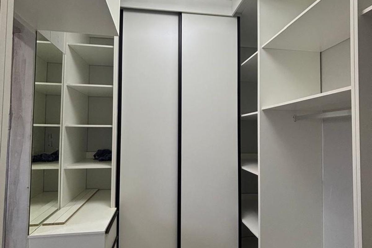 A modern walk-in closet or dressing area featuring extensive built-in cabinetry, shelving, and a contemporary geometric ceiling light fixture.