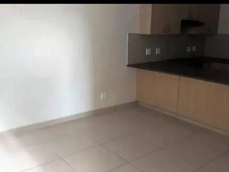 An open-plan living and kitchen area featuring tiled flooring and built-in cabinetry with laminate countertops.