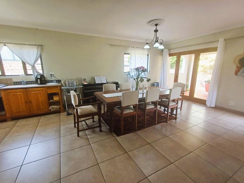 Spacious dining area featuring tiled flooring, a decorative ceiling rose with pendant lighting, and sliding glass doors providing access to the outdoor patio.