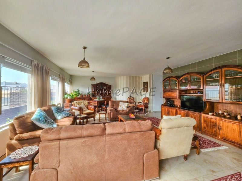 Spacious open-plan living area featuring tiled flooring, large sliding glass doors for natural light, and classic pendant lighting fixtures.