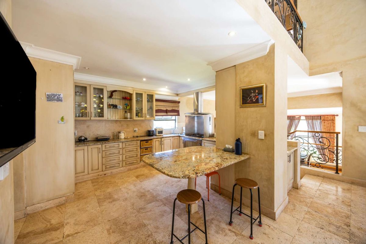 Spacious kitchen featuring granite countertops, ample built-in cabinetry, and stone tile flooring, seamlessly integrated into an open-plan living area with a mezzanine level.