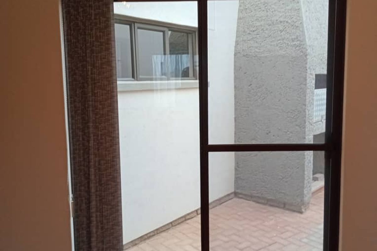 Interior view of a living area featuring a sliding glass door with vertical blinds, providing access to an outdoor patio space.