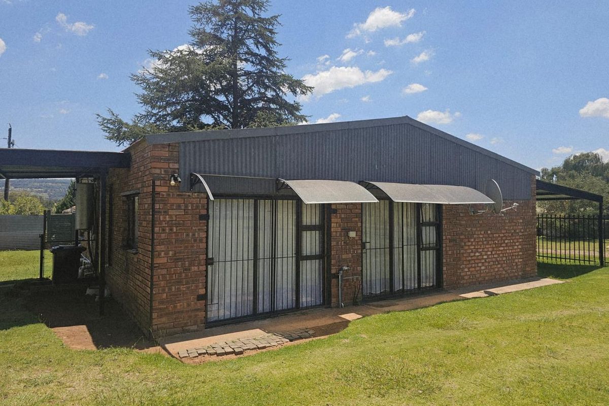 Rear exterior view of a brick house featuring sliding glass doors with security gates, metal awnings, and a corrugated metal roof section.
