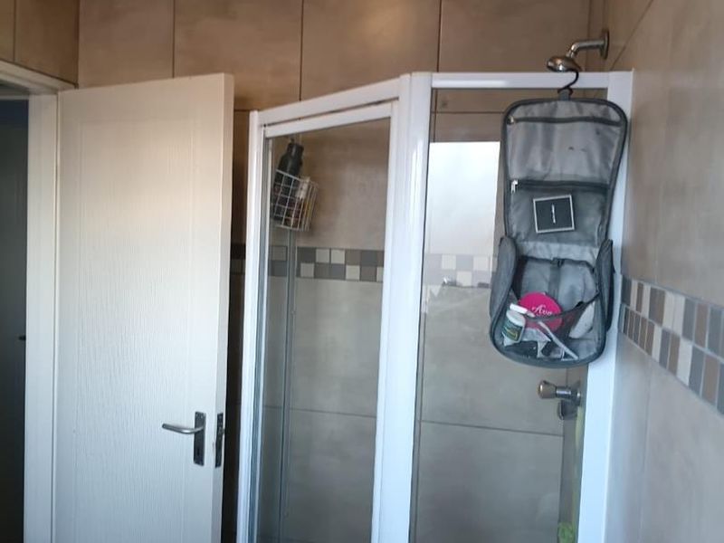 A functional bathroom featuring a corner shower enclosure with tiled walls and flooring.