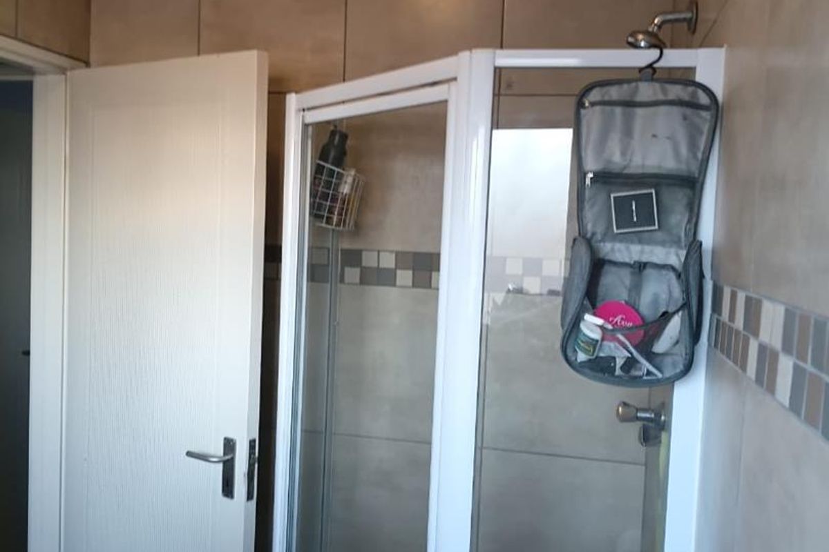 A functional bathroom featuring a corner shower enclosure with tiled walls and flooring.
