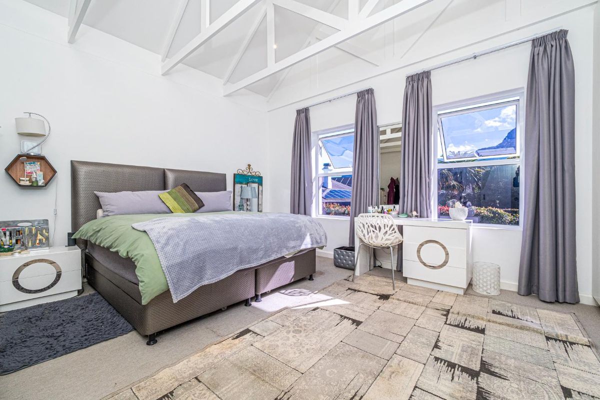 Spacious bedroom featuring high vaulted ceilings with exposed trusses, large windows providing ample natural light, and neutral carpeting.