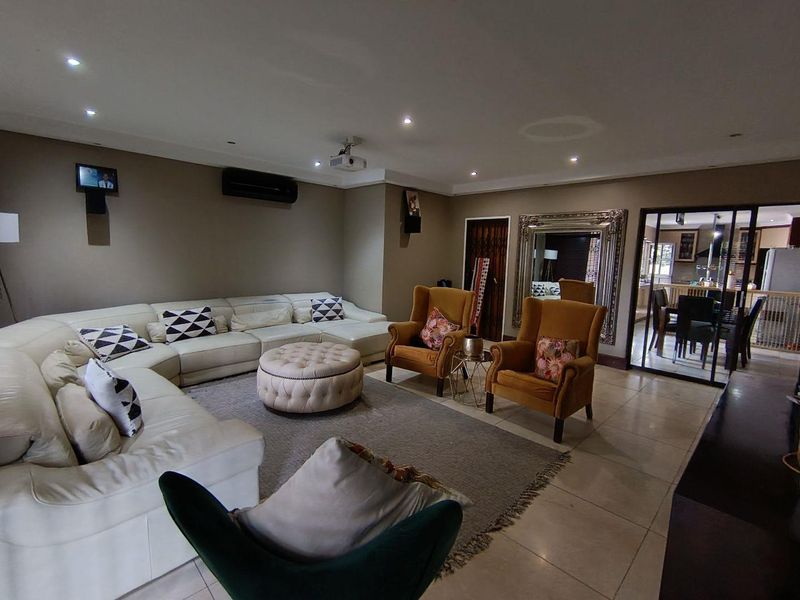 Spacious living room featuring tiled flooring, recessed downlighting, and an integrated air conditioning unit, with a view through to the adjacent dining area.