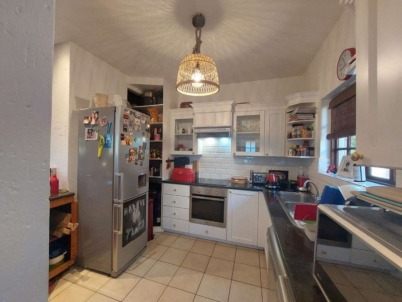 A functional kitchen featuring white cabinetry, subway tile backsplash, dark countertops, and ceramic floor tiles, providing a practical workspace for daily cooking.