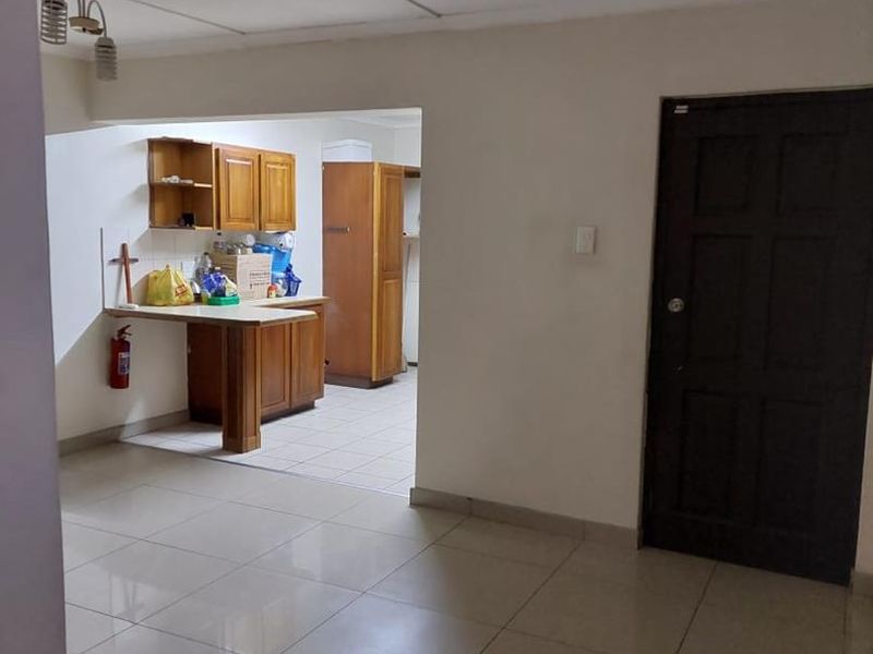 Open plan living area featuring tiled flooring and a functional kitchen nook with built-in wooden cabinetry and a breakfast counter.