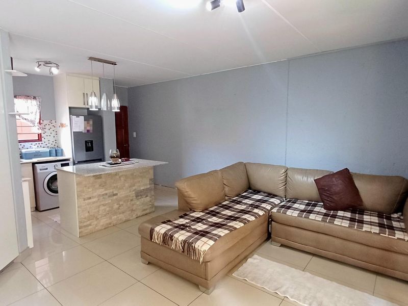 Open-plan living area featuring a kitchen with a stone-clad island, built-in cabinetry, and tiled flooring throughout.