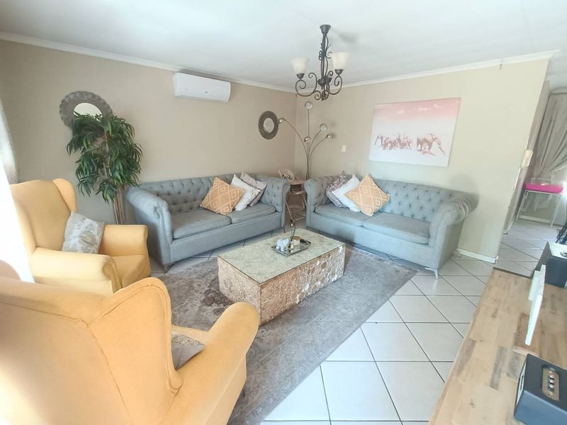 A comfortable living room featuring ceramic floor tiles, a wall-mounted split-system air conditioner, and decorative ceiling lighting.