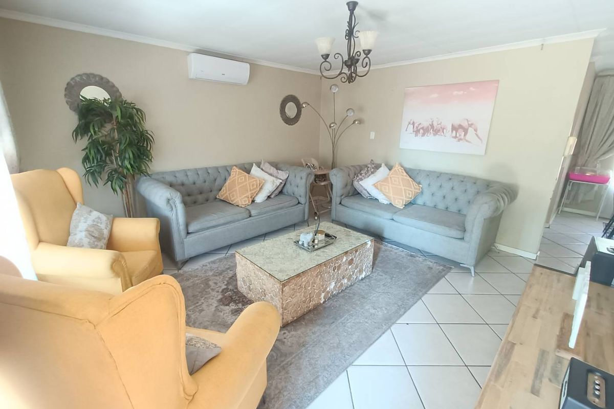 A comfortable living room featuring ceramic floor tiles, a wall-mounted split-system air conditioner, and decorative ceiling lighting.