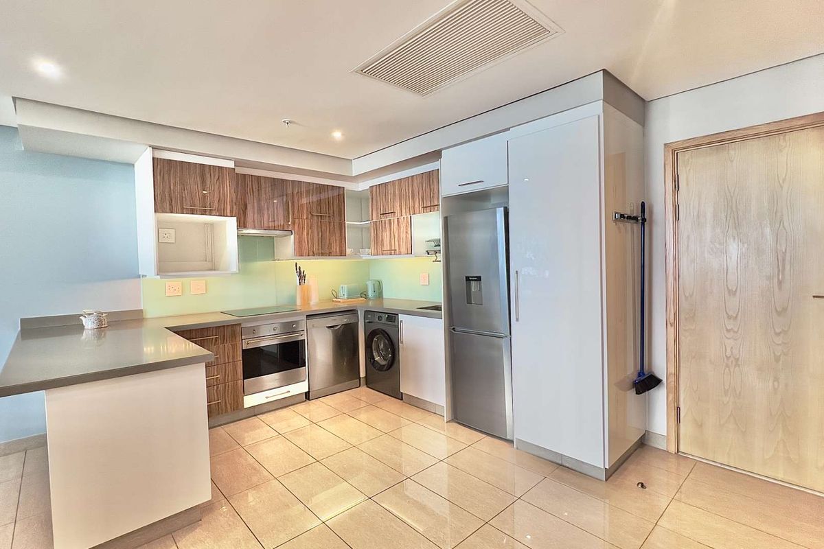 Modern kitchen featuring wood-grain and white cabinetry, stone countertops, integrated appliances, and tiled flooring in an open-plan layout.