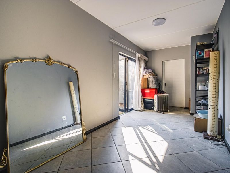 A living area featuring tiled flooring and a sliding glass door providing access to the exterior, with neutral grey wall finishes.
