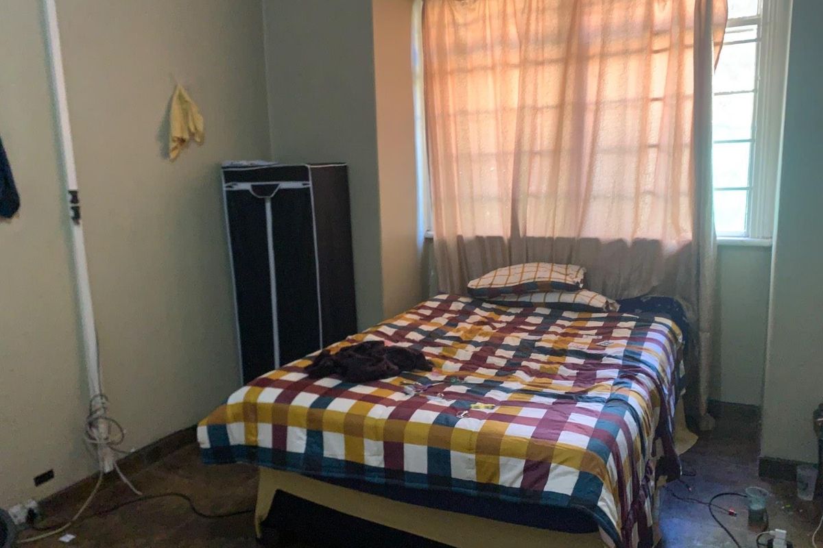 A bedroom featuring a large window with curtains and basic flooring.
