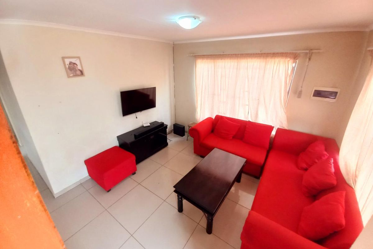 A living room featuring tiled flooring and a wall-mounted television setup, providing a functional and comfortable space for relaxation.