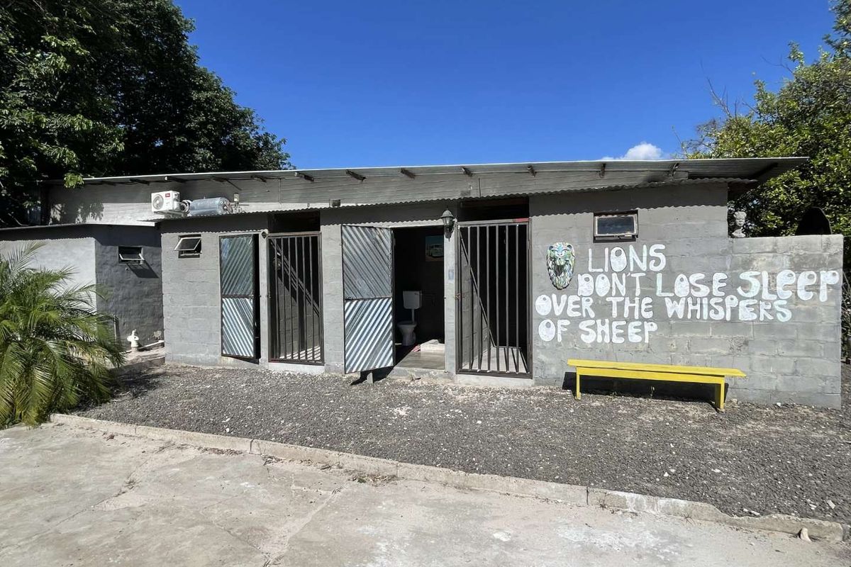 Exterior view of an industrial-style building featuring concrete block construction, metal security gates, and an outdoor area with gravel surfacing.