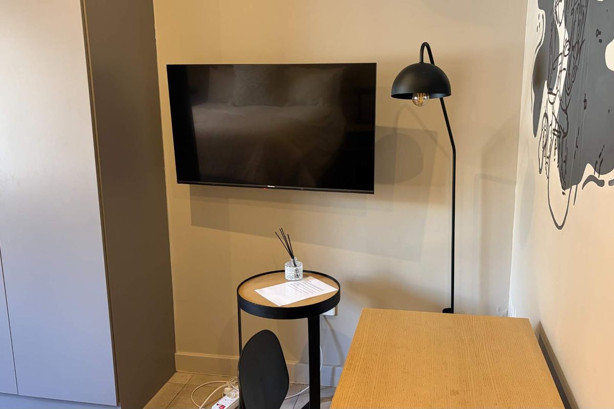 A bedroom interior featuring a built-in wardrobe and a wall-mounted television.