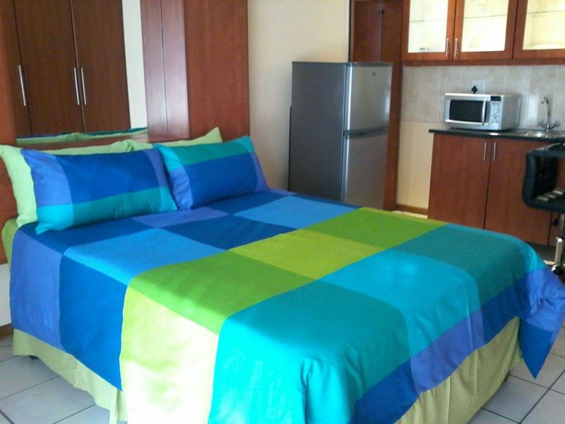 Open-plan studio apartment featuring a combined bedroom and kitchenette area with built-in cabinetry and tiled flooring.