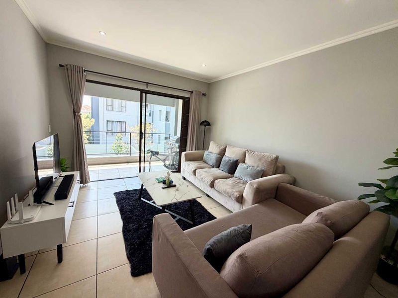 A well-lit living room featuring tiled flooring and large sliding glass doors that provide direct access to a private balcony.