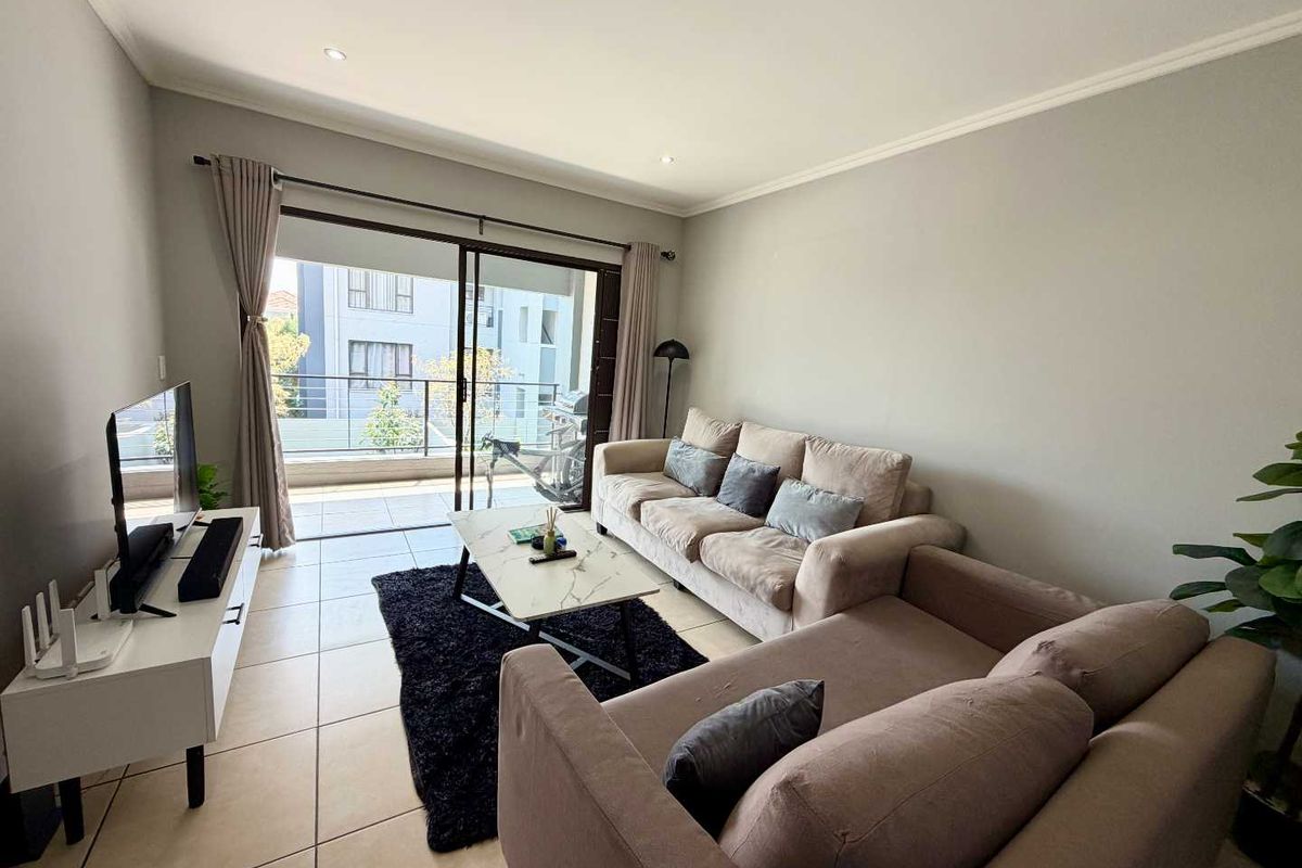 A well-lit living room featuring tiled flooring and large sliding glass doors that provide direct access to a private balcony.