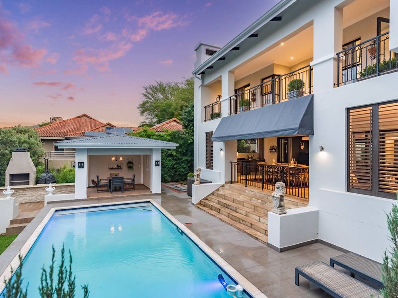 A beautifully maintained rear exterior featuring a swimming pool, covered patio, upper-level balconies, and a dedicated outdoor fireplace area.