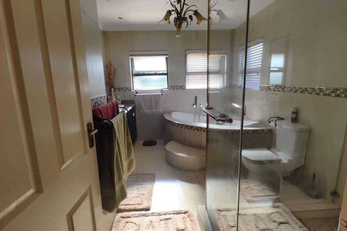 A functional bathroom featuring a corner bathtub, glass-enclosed shower, and tiled flooring with neutral wall finishes.
