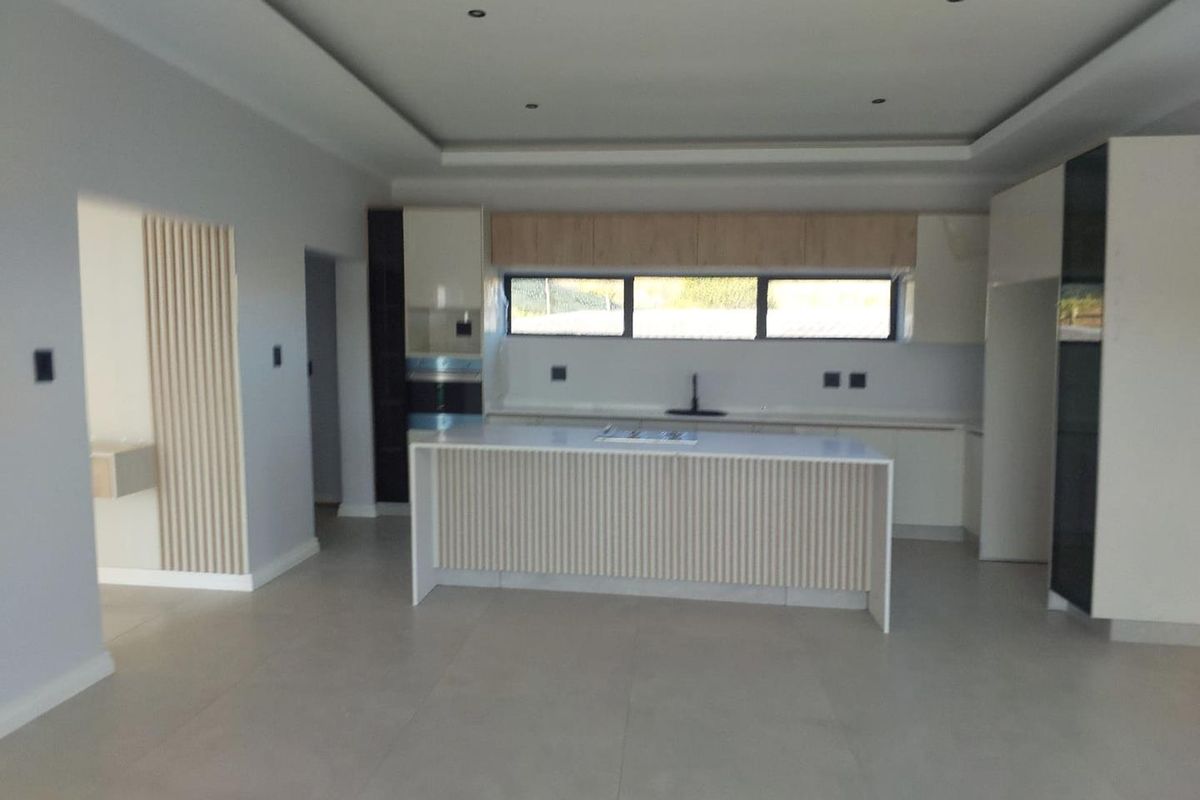 Modern, spacious kitchen featuring a central island, sleek built-in cabinetry, recessed ceiling lighting, and neutral tiled flooring in an open-plan layout.