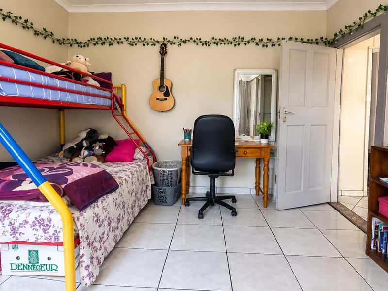 A functional bedroom featuring tiled flooring and neutral wall finishes, providing a versatile space for rest or study.