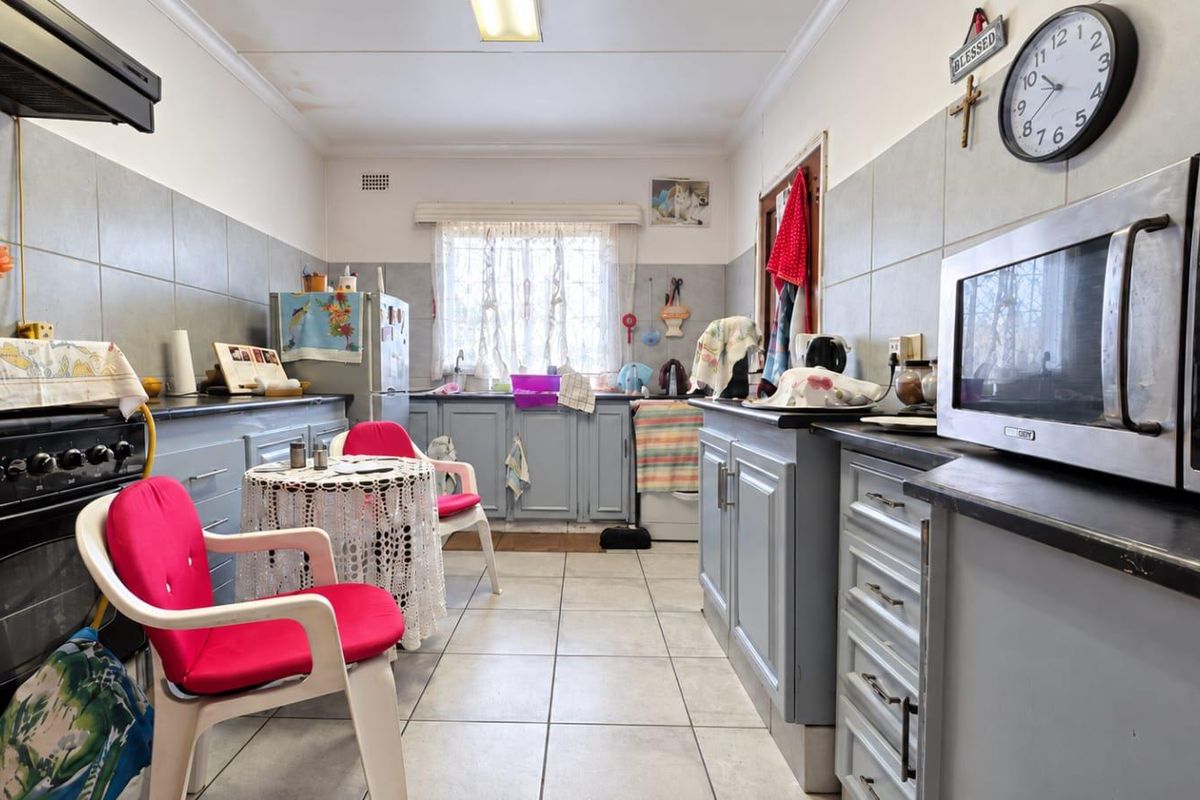 A functional kitchen featuring tiled flooring, grey cabinetry, a built-in oven, and a tiled backsplash, with visible signs of ceiling water damage.