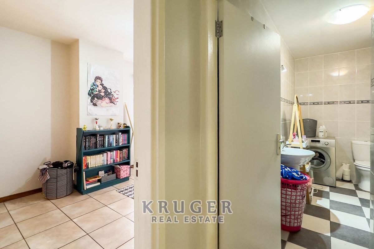 A functional bathroom featuring tiled flooring, a pedestal basin, and a toilet, with integrated laundry plumbing connections.