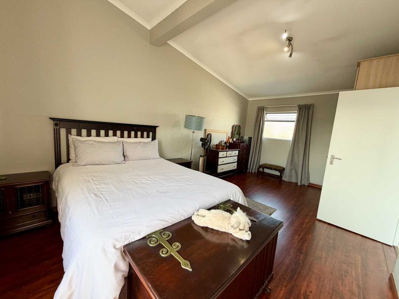 Spacious bedroom featuring warm-toned laminate flooring, neutral wall finishes, and a built-in wardrobe, offering a comfortable and functional living space.