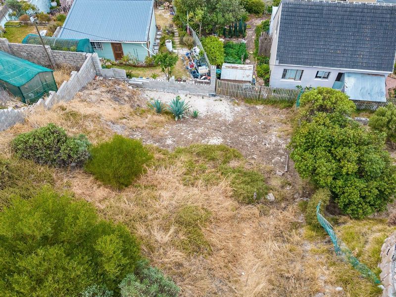 An aerial view of a vacant residential plot showing existing boundary fencing, retaining walls, and natural vegetation cover.