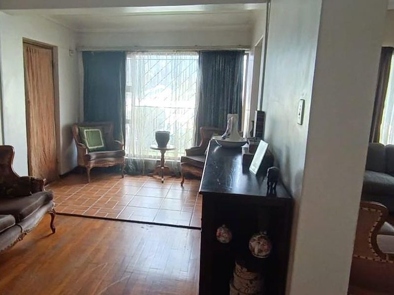 Open plan living area featuring a combination of parquet and tiled flooring with large windows and security bars.