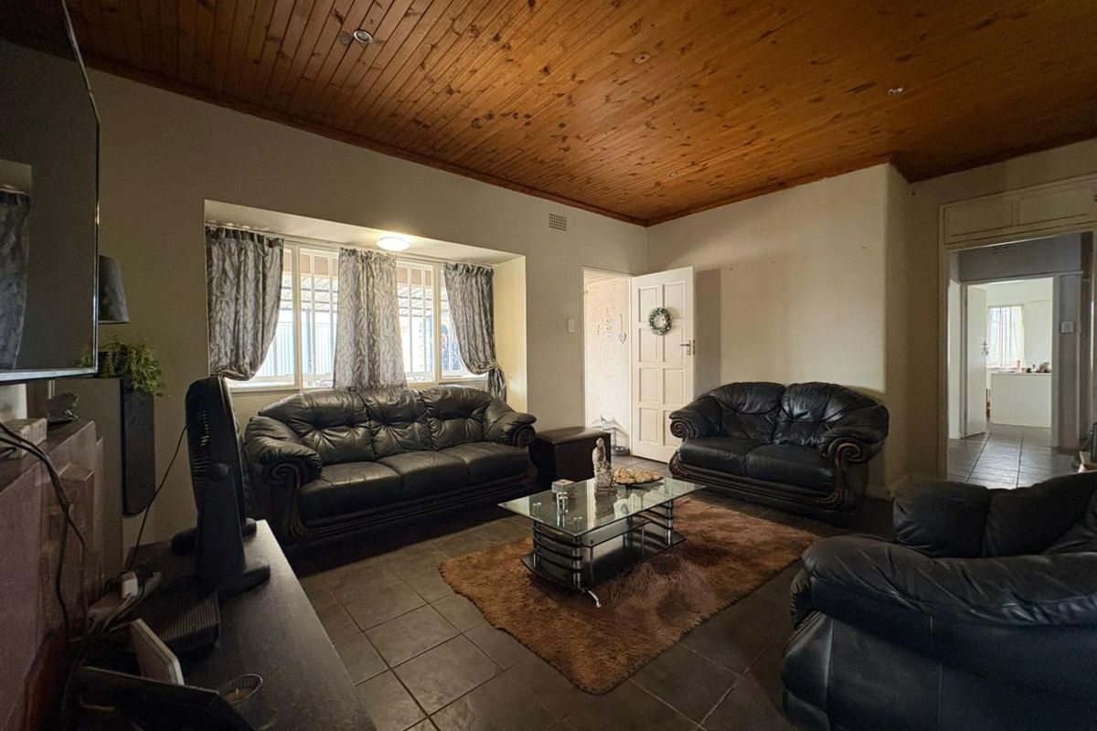 A living room featuring a timber tongue and groove ceiling, tiled flooring, and security bars on the windows.