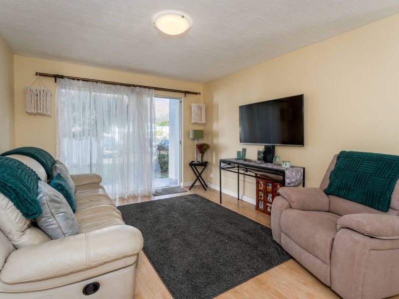 A comfortable living room featuring laminate flooring, a flush mount ceiling light, and a sliding glass door providing access to the exterior.