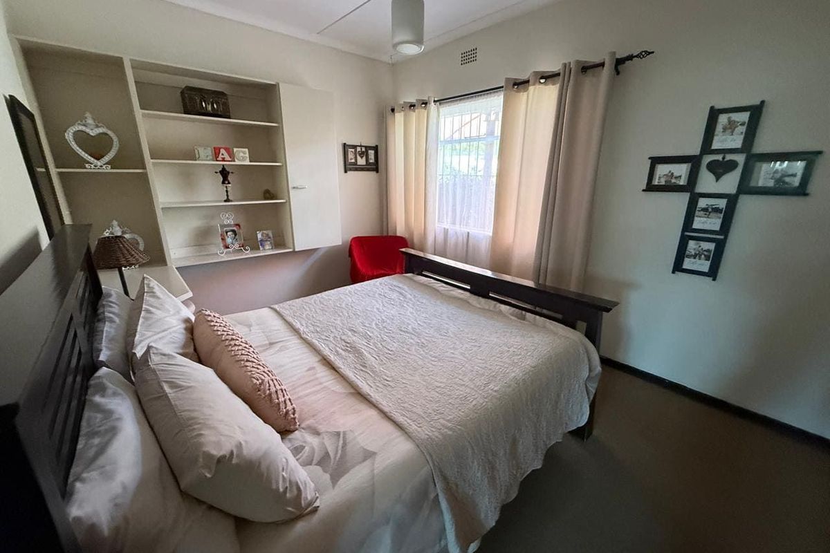 A bedroom featuring built-in shelving units, a window with curtain rods, and neutral wall finishes.