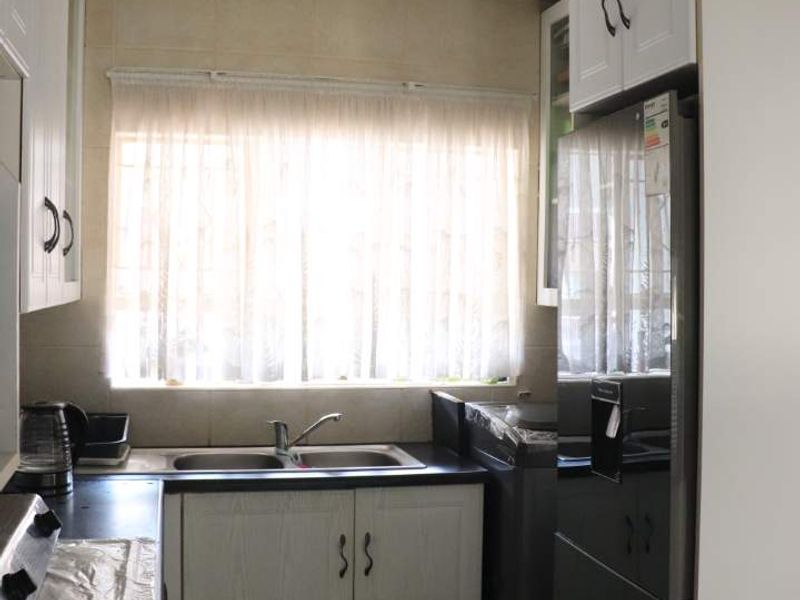 A functional kitchen featuring built-in cabinetry, double sink with mixer tap, laminate countertops, and tiled flooring, offering a practical layout for daily use.