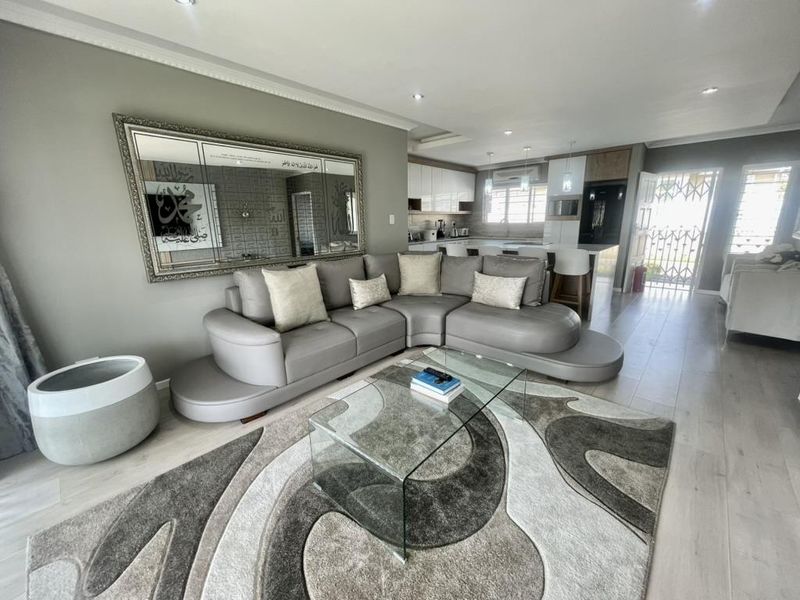 Spacious open-plan living area featuring modern laminate flooring, recessed lighting, and a contemporary kitchen with a central island and sleek cabinetry.