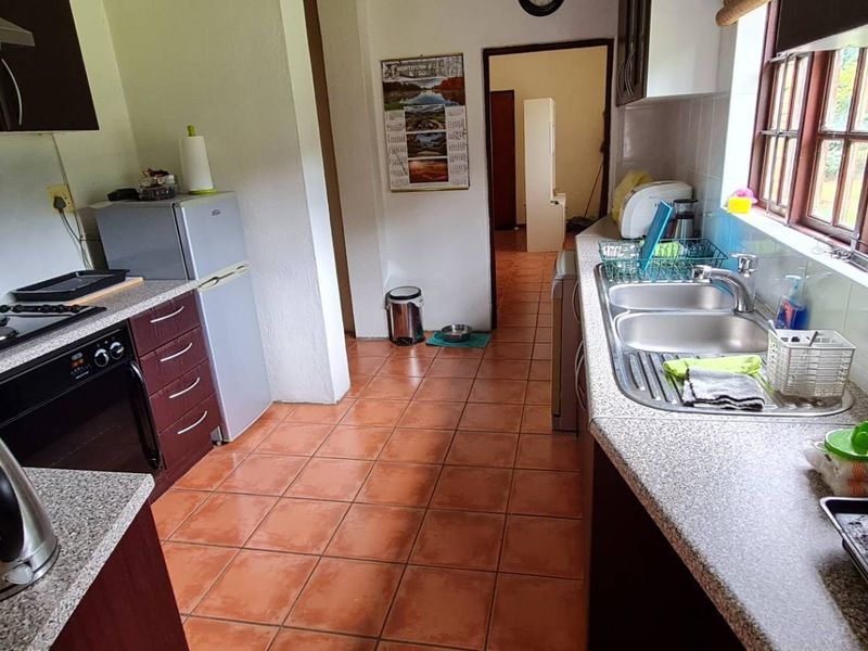 Functional kitchen featuring built-in cabinetry, electric hob, oven, extractor fan, and a double basin stainless steel sink with tiled flooring and backsplash.