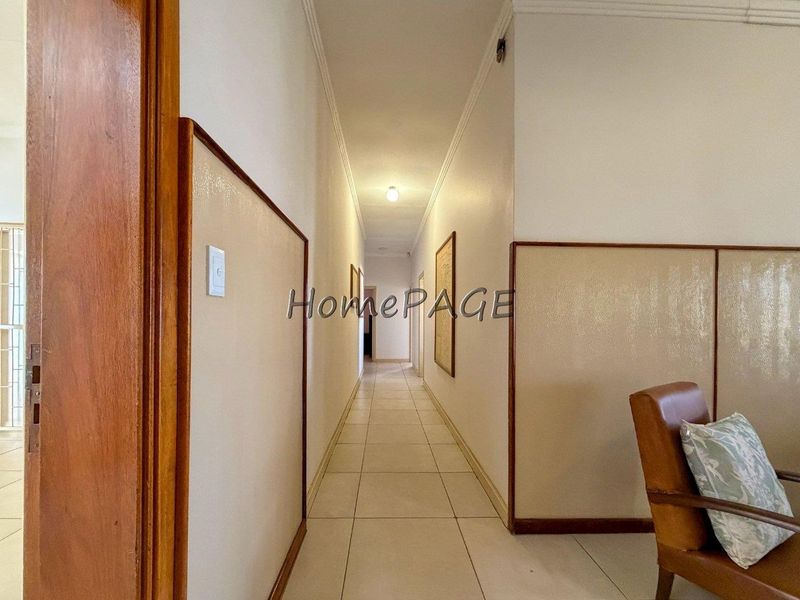 A long, tiled hallway featuring timber door frames and decorative wall paneling, providing access to various rooms within the home.