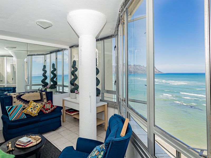 Enclosed balcony featuring large aluminum-framed windows, a structural column, and expansive ocean views, providing a bright and versatile living space.