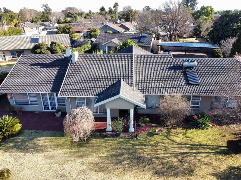 Aerial view of a residential property featuring a tiled roof, solar water heating system, and a covered entrance porch with a paved patio area.