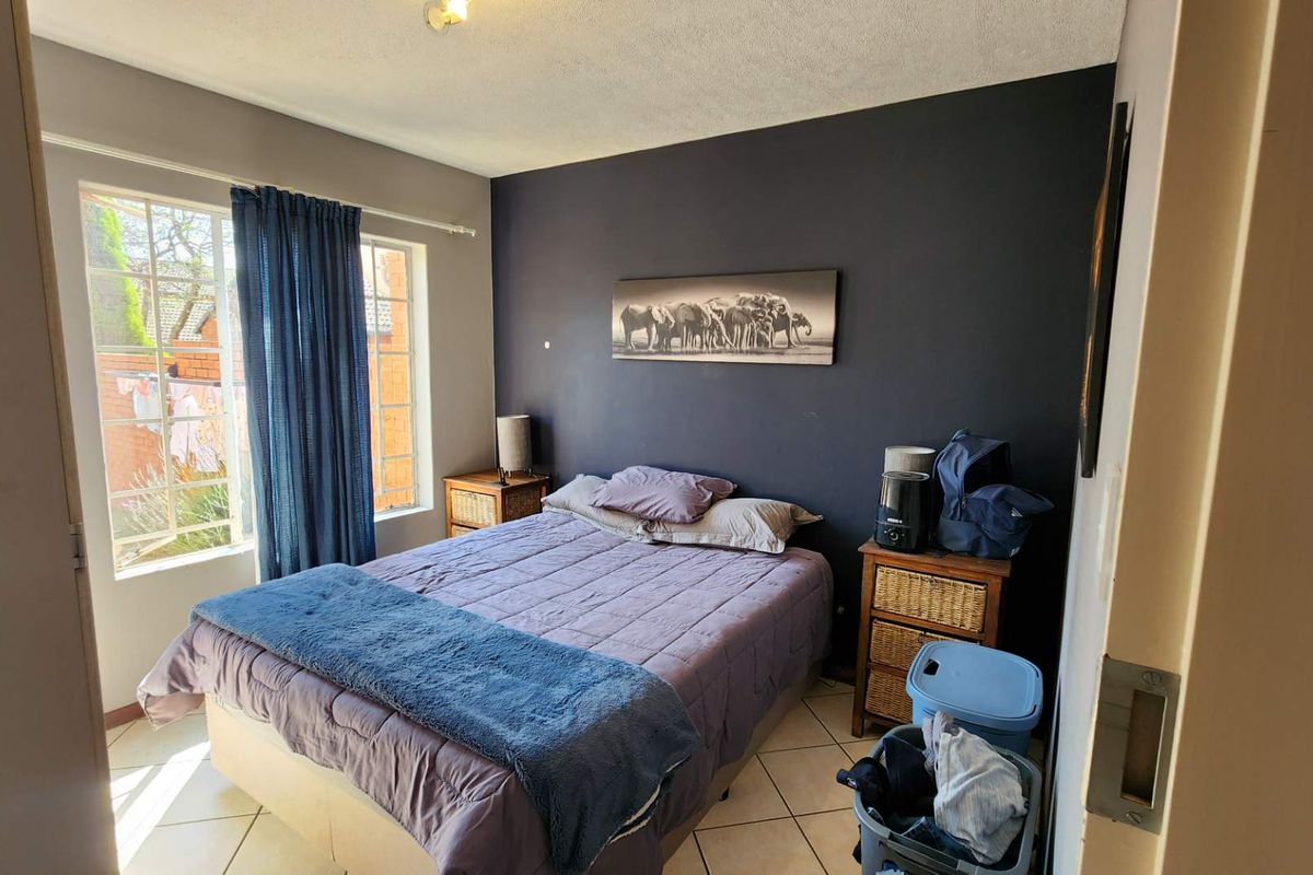 A bedroom featuring tiled flooring and a window, with a dark accent wall providing a focal point for the space.