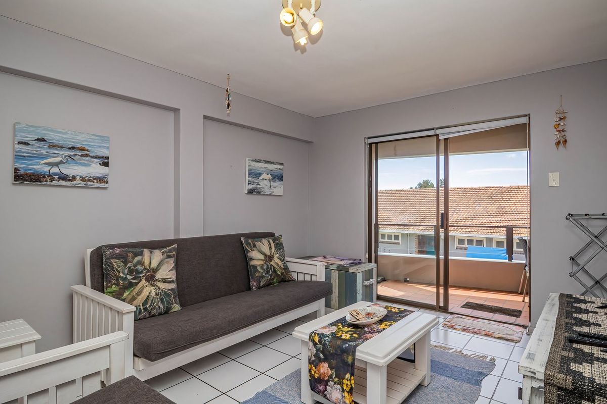 A bright living room featuring tiled flooring and a sliding glass door that provides direct access to an outdoor balcony area.