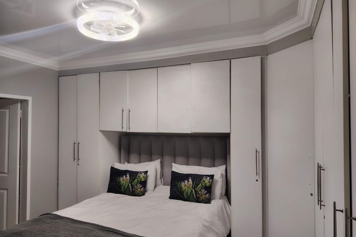 A well-maintained bedroom featuring extensive built-in cabinetry surrounding the bed area, complemented by modern recessed ceiling lighting and crown molding.