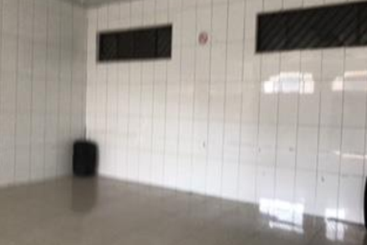 An empty utility space featuring fully tiled walls and flooring with high-level windows, suitable for various commercial or storage purposes.
