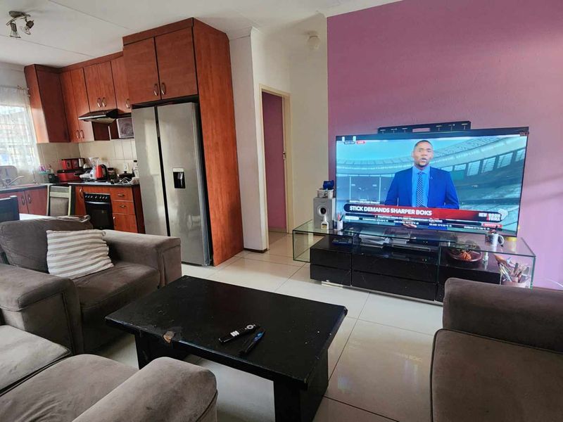 Open-plan living area featuring a combined kitchen with built-in cabinetry and a lounge space with tiled flooring.